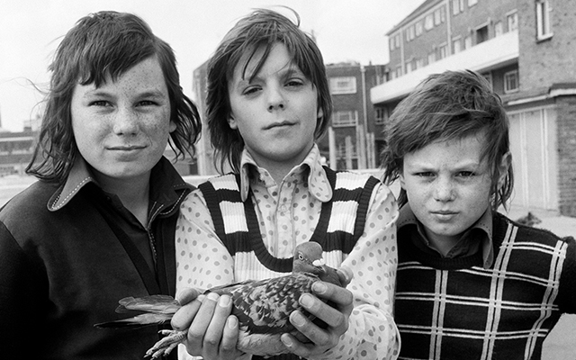 Black-and-white photograph of three children and a pigeon